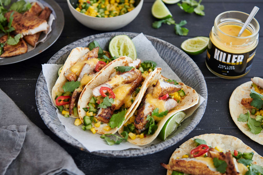 Grilled Fish Tacos with Pine Lime Hot Sauce garnished with fresh corn, cucumber, chili, coriander, and lime slices – Killer Condiments Recipes.