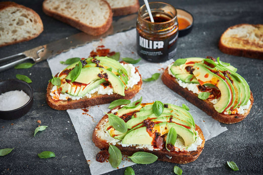 Toasted sourdough bread topped with mashed avocado, feta, Supercharged Crispy Chilli Oil, and basil garnish