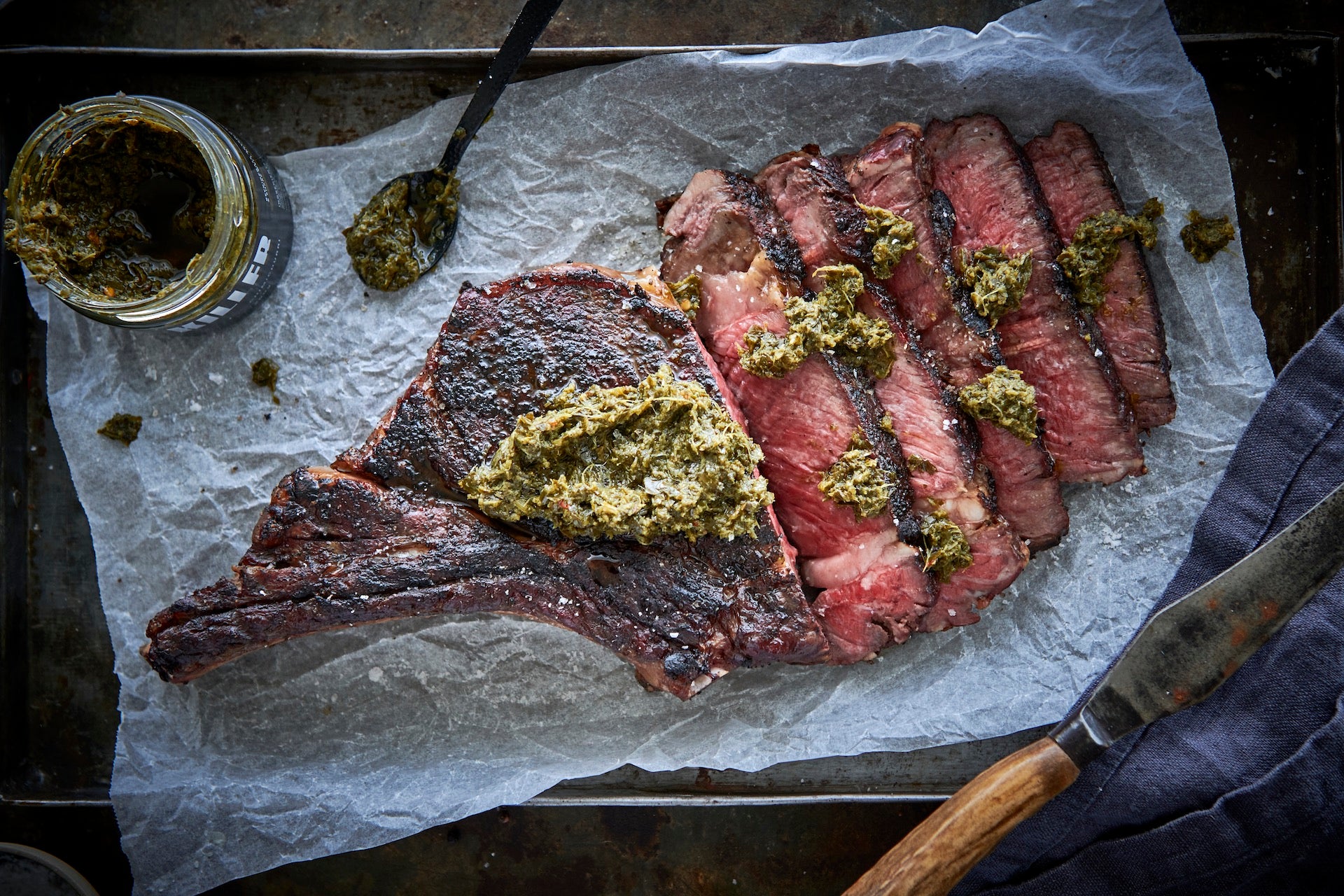 Medium rare rib eye steak elegantly sliced and drizzled with Killer Condiments Chimichurri, adding a vibrant and bold flavor to a classic dish - a perfect find for adventurous food bloggers and gourmet home chefs